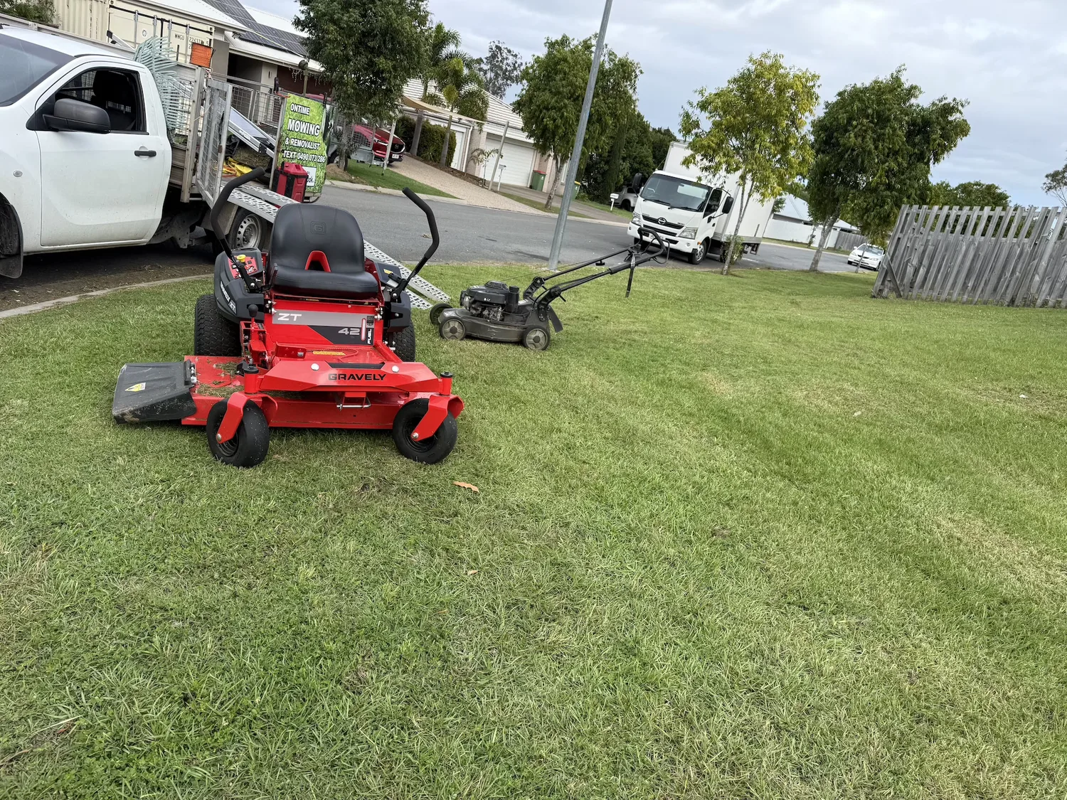 OnTime Landscape & Tree Maintenance ride-on mower on a freshly mowed Brisbane lawn